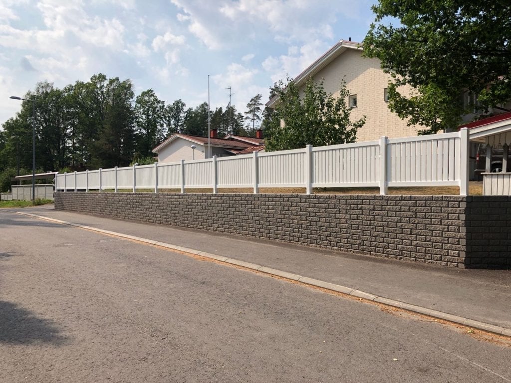 Valkoinen vinyyliaita kiviaidan päällä